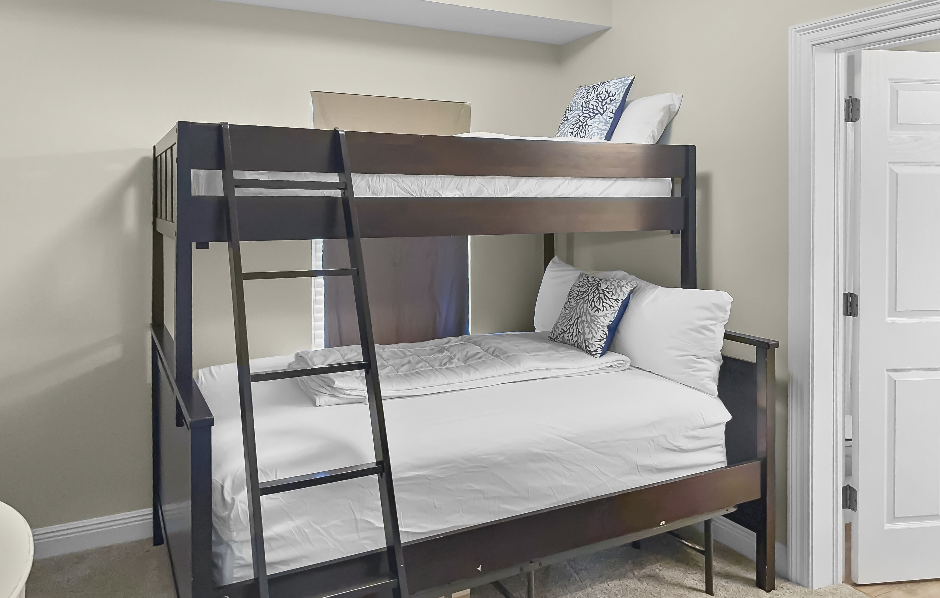 A bunk bed with a ladder, white bedding, and patterned pillows.
