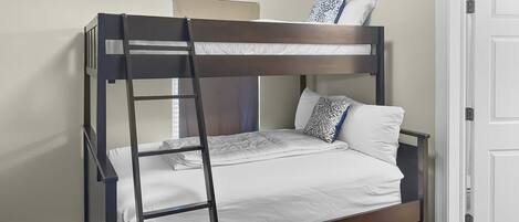 A bunk bed with a ladder, white bedding, and patterned pillows.