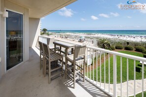 Ein Balkon mit Blick auf den Strand, Outdoor-Möbel und das Legacy Vacations Logo.