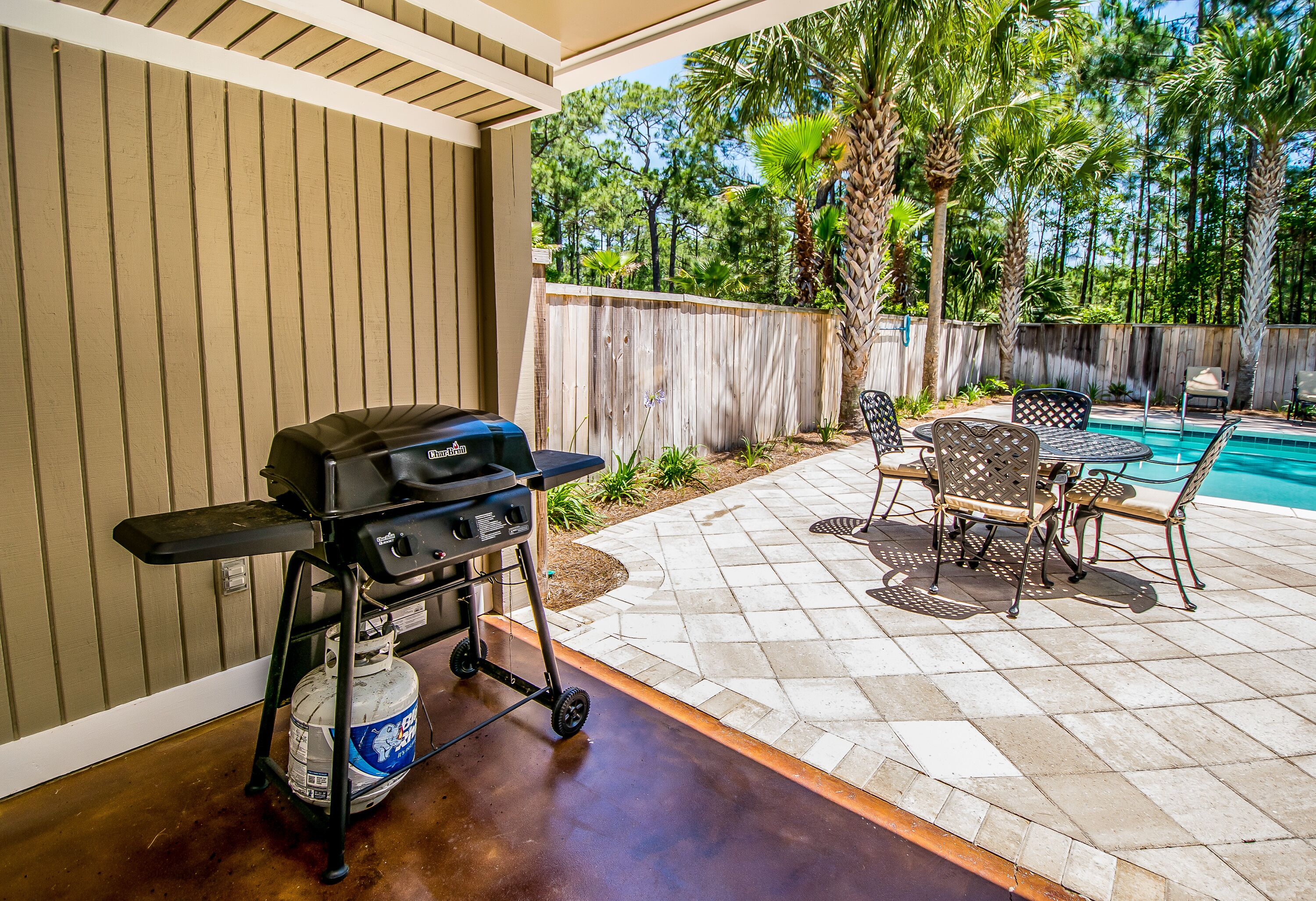 A patio with a grill, outdoor furniture, and a pool.