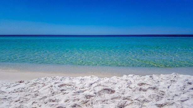Une plage à l’eau turquoise et au sable blanc.