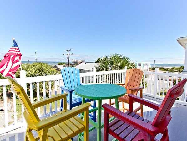 Une terrasse agrémentée de chaises Adirondack aux couleurs vives, d’une petite table ronde et d’un drapeau américain.