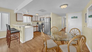 A modern kitchen with a central island, wooden chairs, and a glass dining table.