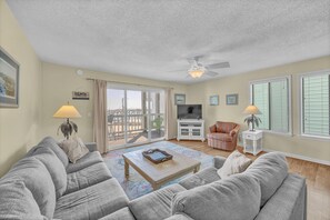 A living room with a sofa, a coffee table, a TV, and a ceiling fan.