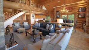Un intérieur spacieux de chalet en bois, comprenant un salon, un coin repas et une cuisine.