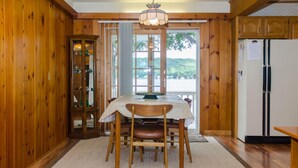 A wooden interior with a dining table and chairs, a cabinet with glass doors, and a refrigerator. - Fun in the Sun - Walk Into Town on Keuka's East Side (Penn Yan)