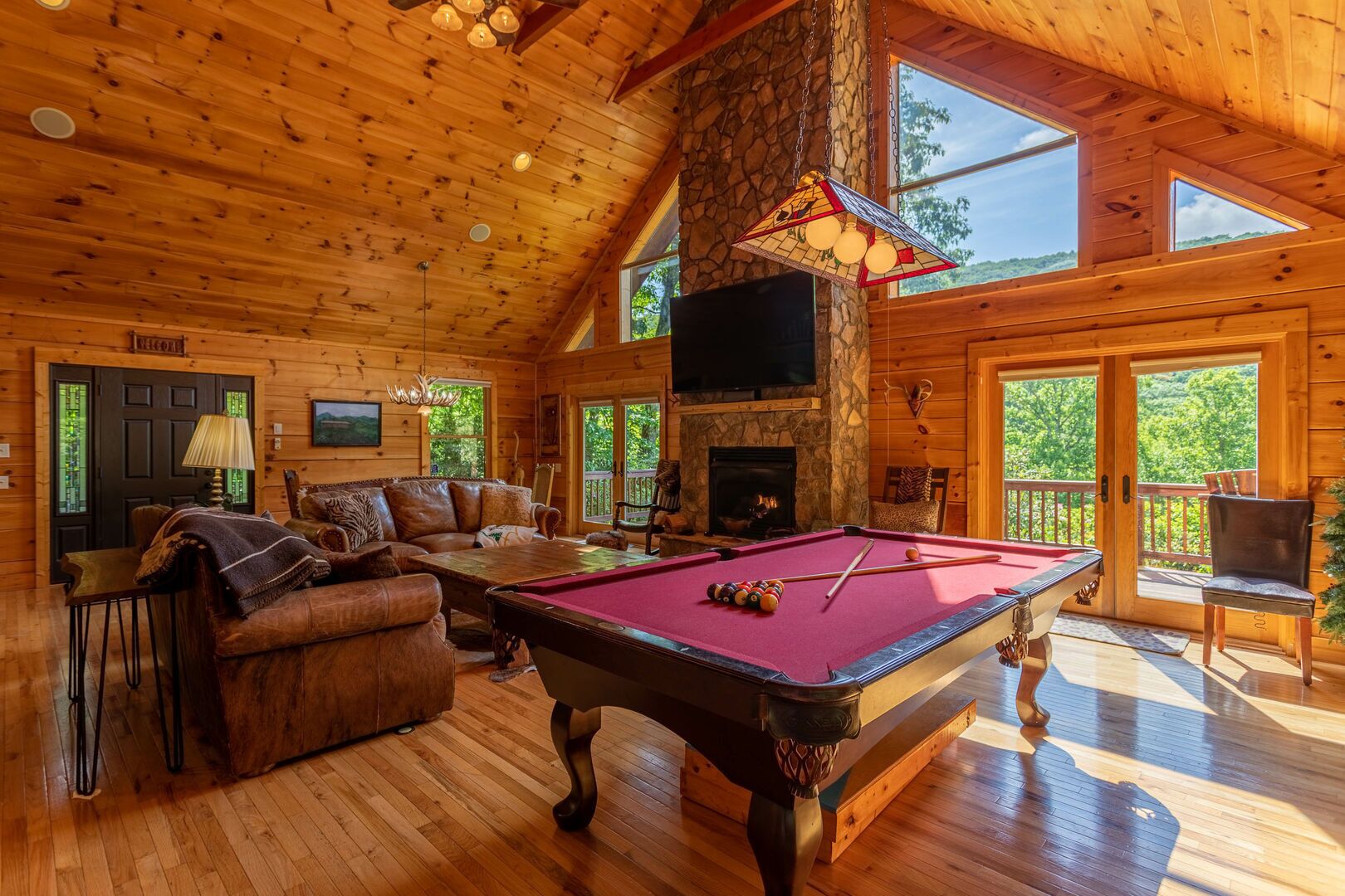 Une pièce spacieuse équipée d’une table de billard, d’un canapé en cuir et d’une cheminée.