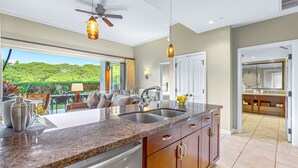 A modern kitchen with granite countertops, stainless steel appliances, and wooden cabinets. - Maui Resort Rentals: Honua Kai Konea 136 – Ground Floor 1BR w/ Lawn Area + Easy Pools/Beach Access (Lahaina)