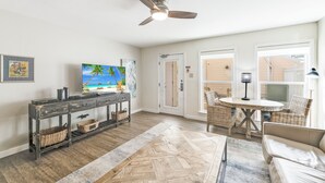 A living room with a television, a ceiling fan, wicker furniture, and a herringbone-patterned rug. - Chic Poolside Condo | Ultimate Beachfront Escape (Corpus Christi)
