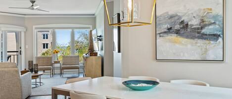 Un comedor moderno con una mesa blanca, cuatro sillas, un tazón azul y una lámpara colgante de diseño geométrico.