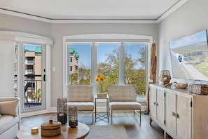 Un salón amplio con ventanas grandes, un sofá, dos sillones, una mesita de centro y un aparador.