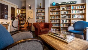 Un salón acogedor con chimenea, una estantería, una guitarra y una exhibición de trenes modelo.