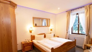 Une chambre à coucher avec un lit en bois, deux tables de chevet, une commode, un miroir et une fenêtre avec des rideaux.