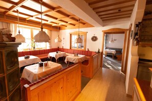 A cozy restaurant with wooden booths and tables, a fireplace, and a view of the snowy outdoors.
