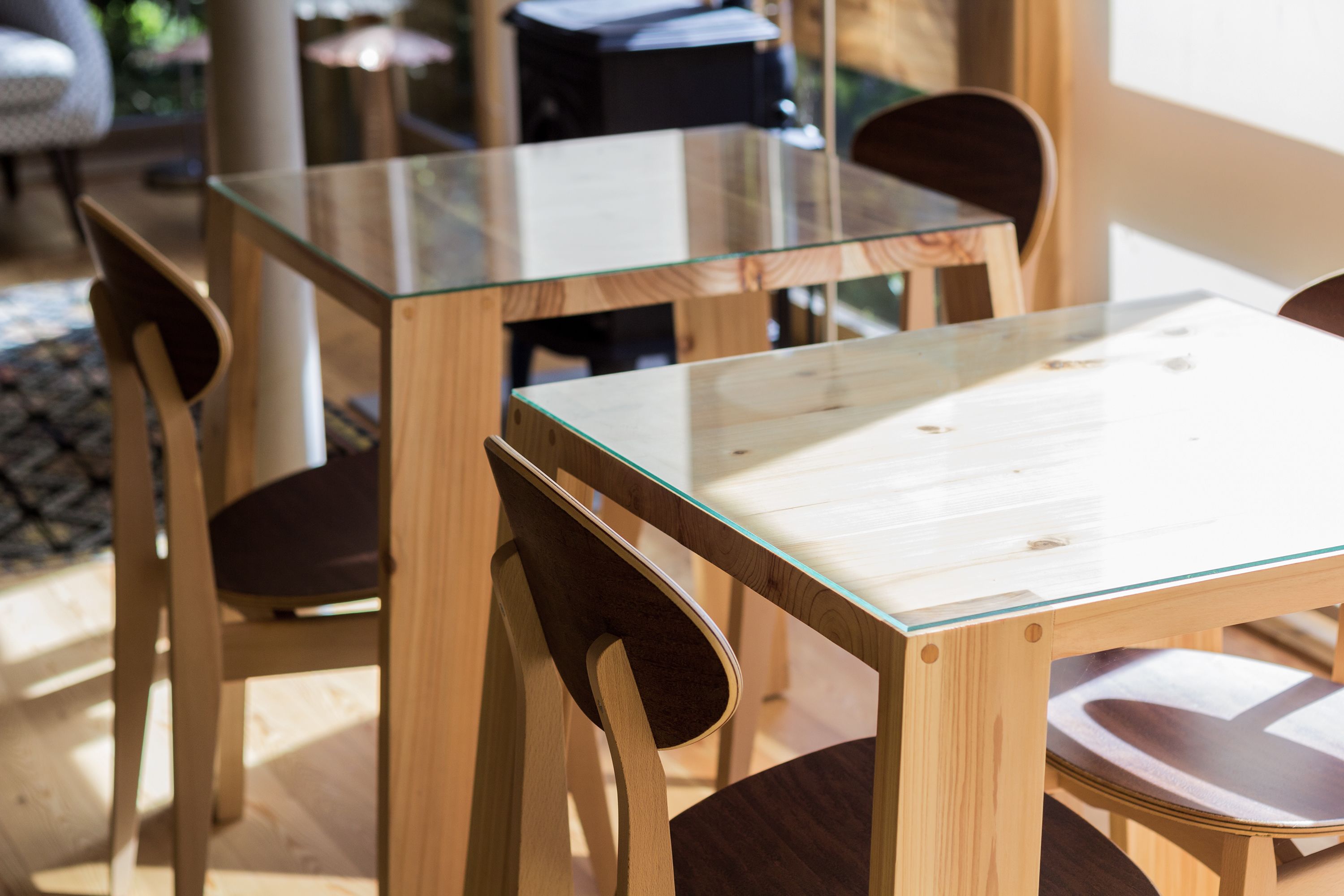A wooden table with a glass top, surrounded by wooden chairs.