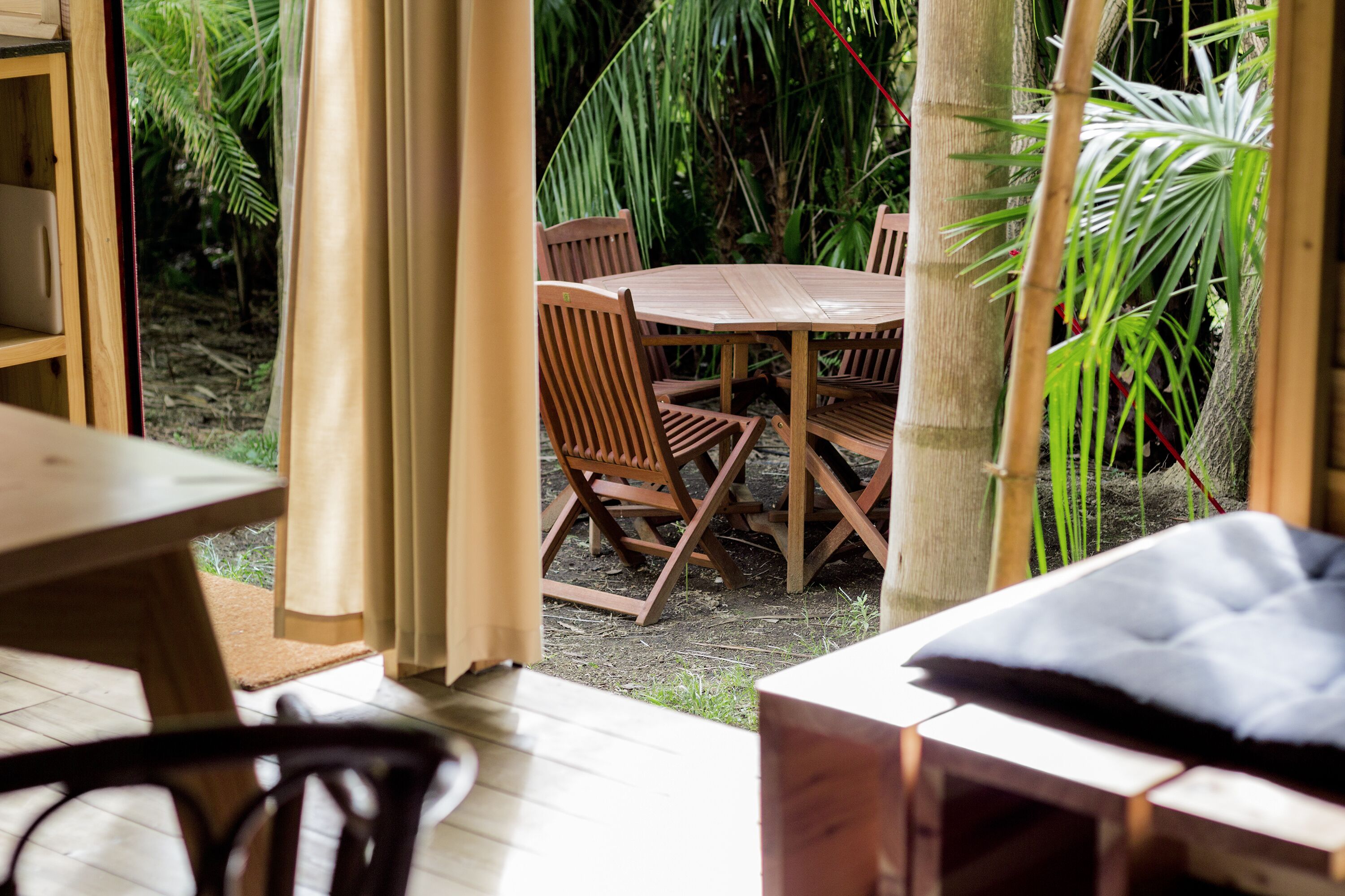 Un conjunto de mesa y sillas de madera al aire libre en un jardín con exuberante follaje.