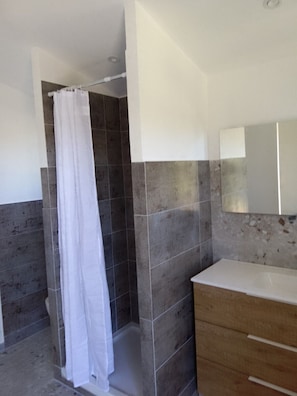 A bathroom with a shower, a vanity with a mirror, and tiled walls. - Domaine l'Helion (Taradeau)