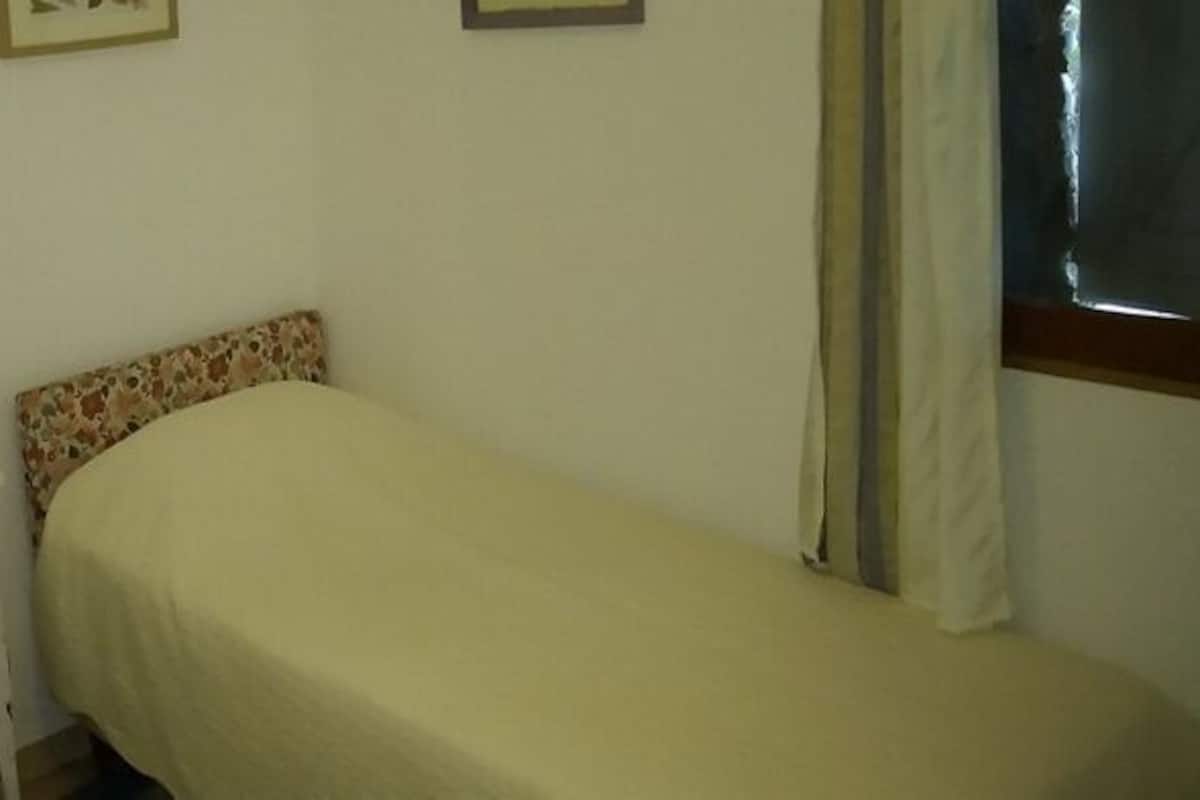 A small room with two beds, a white nightstand, and a painting on the wall.
