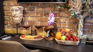 A bar area with a brick wall, a mounted TV, and a variety of food and drink items on the counter. -  BİG URBAN STAY TAKSİM@WİTH SEA VİEW (Istanbul)