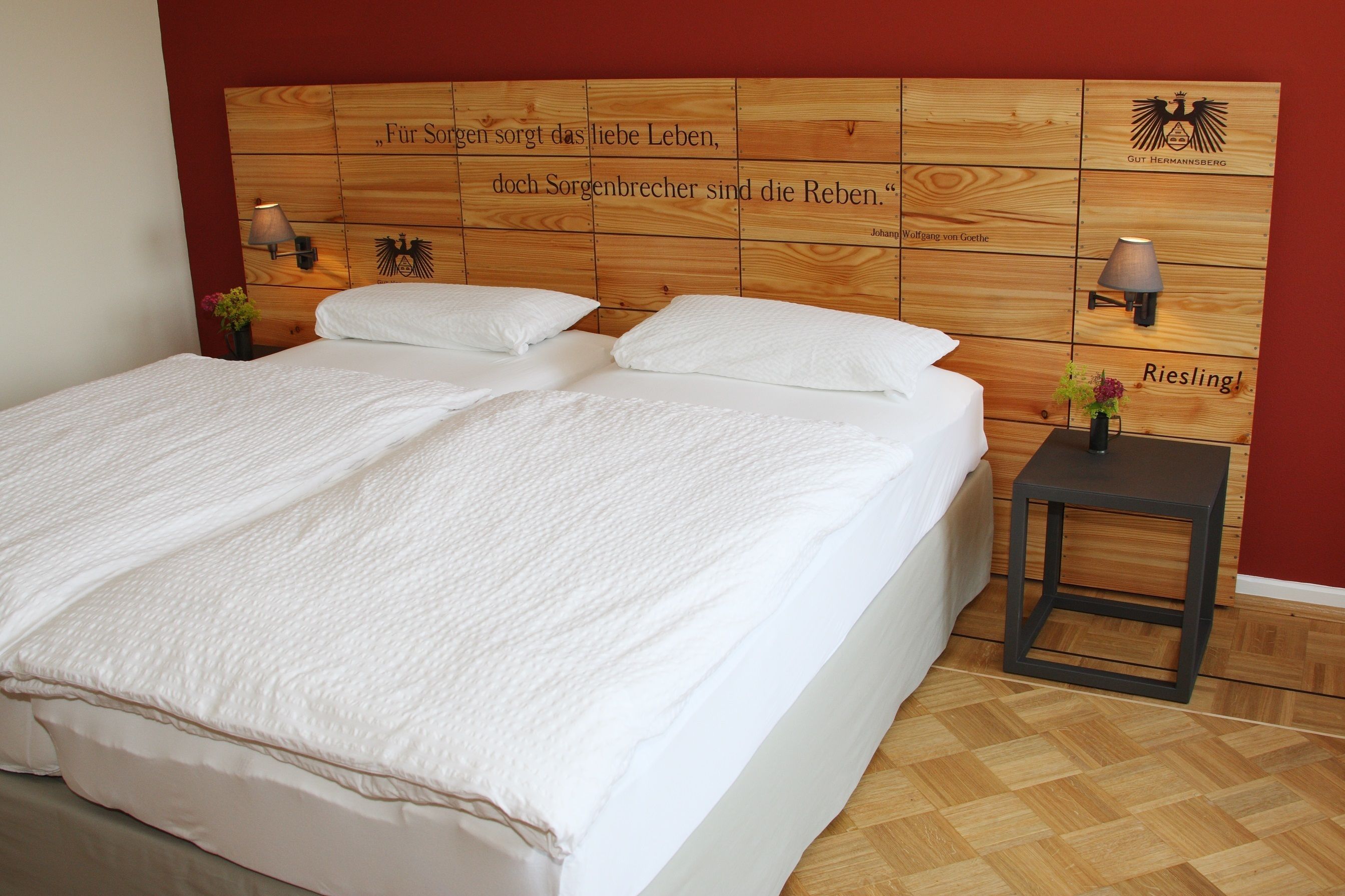 A neatly made bed with white linens in a room with wooden headboard and two wall-mounted lamps.