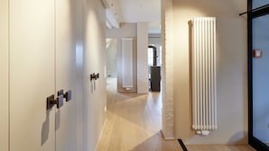 Un couloir moderne avec un plancher en bois, des murs blancs et un radiateur.