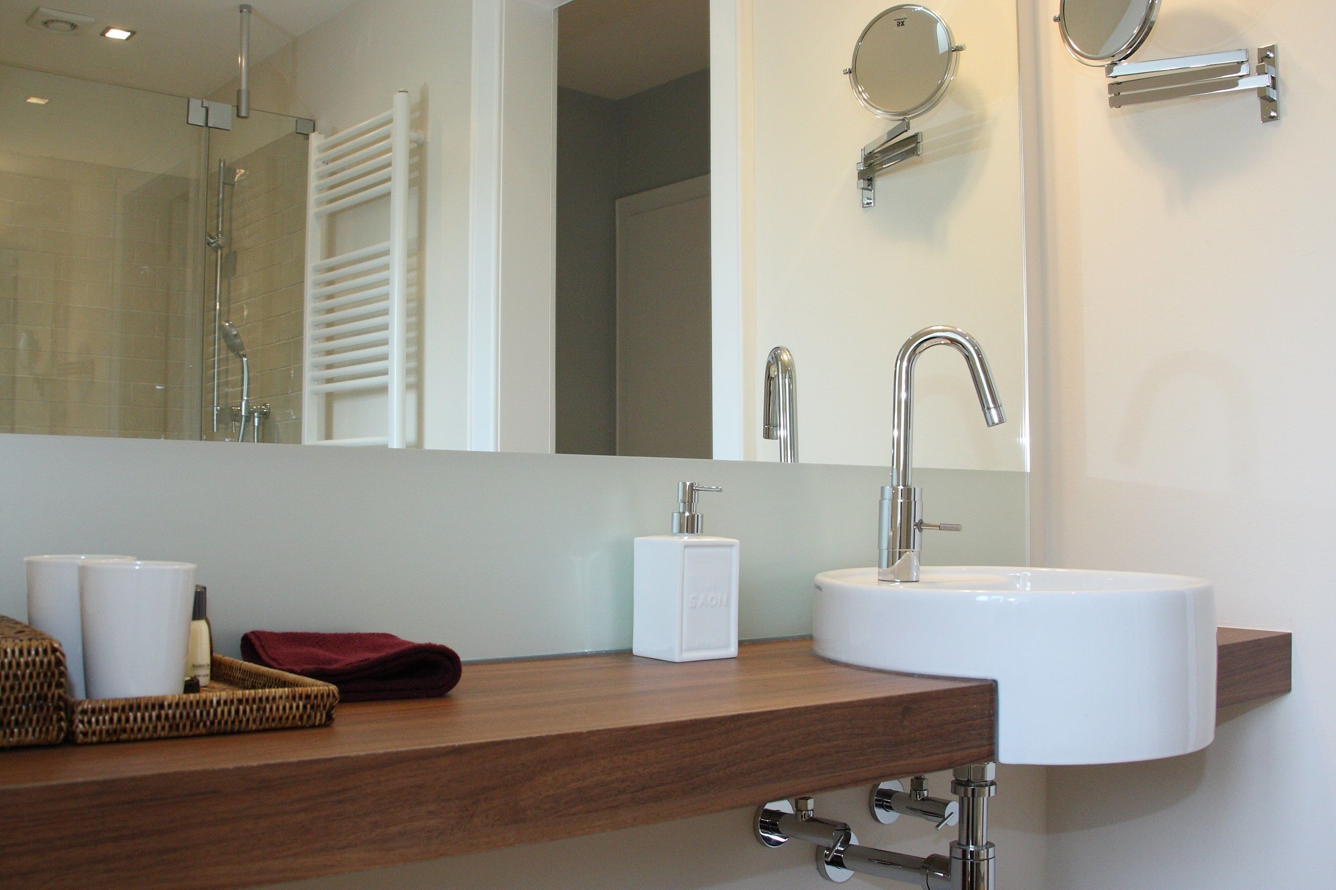 A bathroom with a white sink, a mirror, a towel rack, and a shower area.
