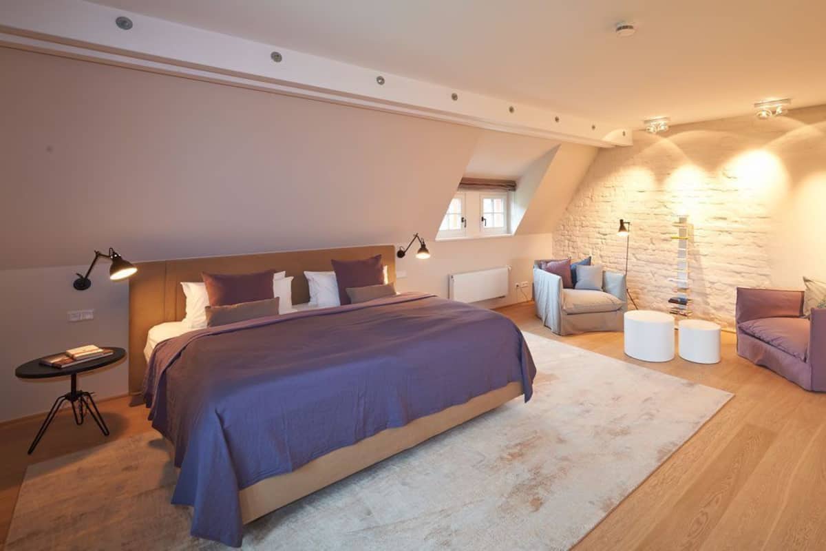 Un dormitorio con una cama grande, una mesita, una silla y una lámpara.