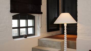 A staircase with a concrete finish, a white wall, and a window with a black frame.