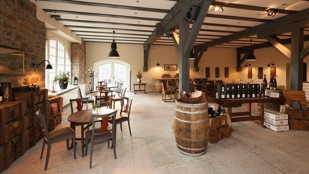Un intérieur rustique avec des poutres apparentes, un mur en pierre, un tonneau en bois et un meuble à bouteilles de vin.
