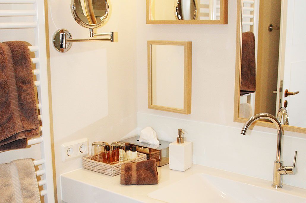 A bathroom with a white sink, a mirror, a towel rack, and a shelf with toiletries.