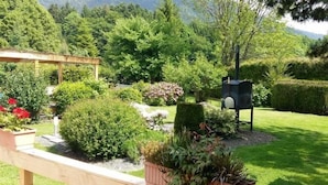 A wooden bench with potted plants, a mailbox, and a well-maintained garden with various shrubs and flowers. - L'usine (Belval)