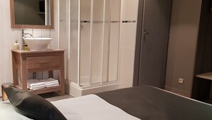 A bedroom with a bed, a bedside table with a mirror, a white sink, a wardrobe, and a door. - L'usine (Belval)