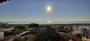 A coastal town with a clear view of the sea and a bright sun in the sky.