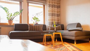 Ein modernes Wohnzimmer mit einer Couch, einem Glastisch und zwei Blumentöpfen.