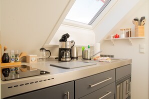 A modern kitchen with a skylight, stainless steel appliances, and wooden shelves. - Appartement Ludwigskanal (Schwarzenbruck)