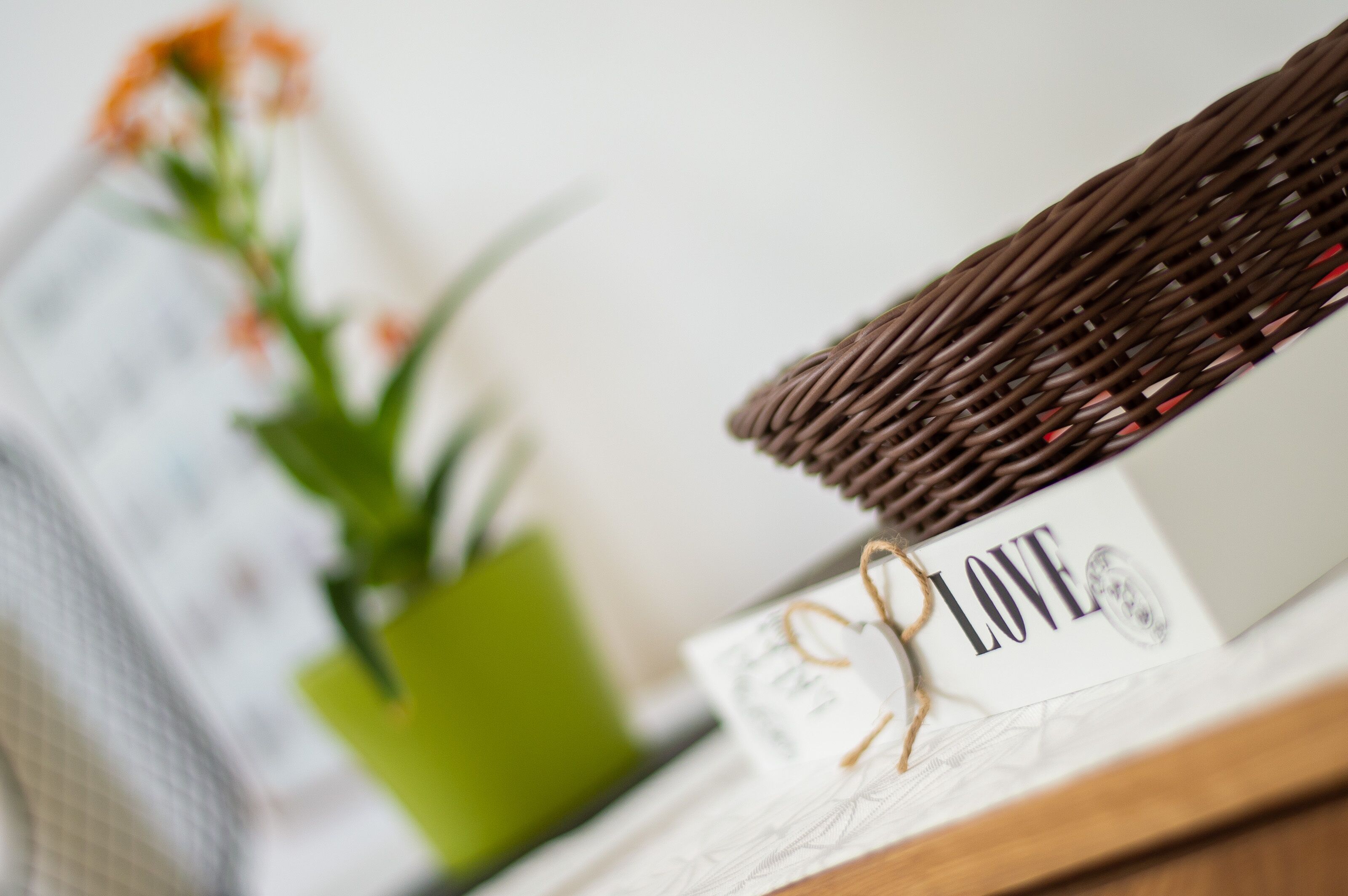 Un panier en osier, posé sur une surface en bois, avec une carte sur laquelle est écrit le mot « AMOUR ».