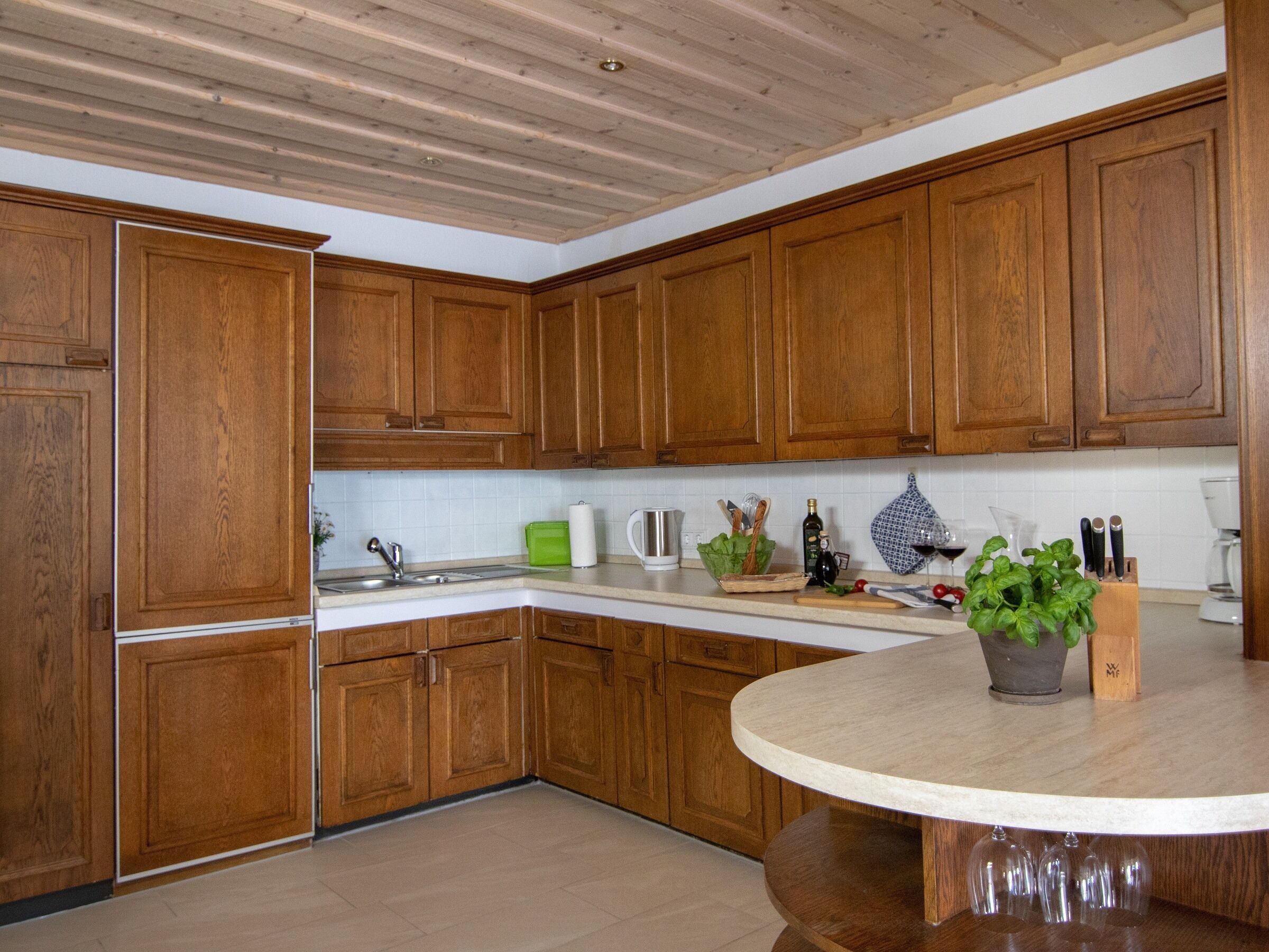 Eine Küche mit Holzschränken, einem Spülbecken, einer Arbeitsplatte und einem runden Tisch mit einem Blumentopf.