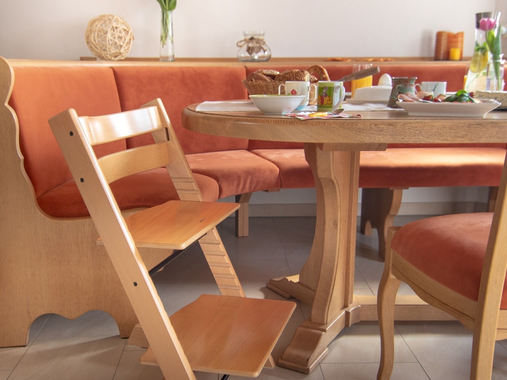 A wooden dining table with a bench, surrounded by a cushioned seating area.