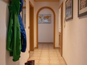 A hallway with a tiled floor, a map on the wall, and a coat rack with green and blue jackets. - Appartement Ludwigskanal (Schwarzenbruck)