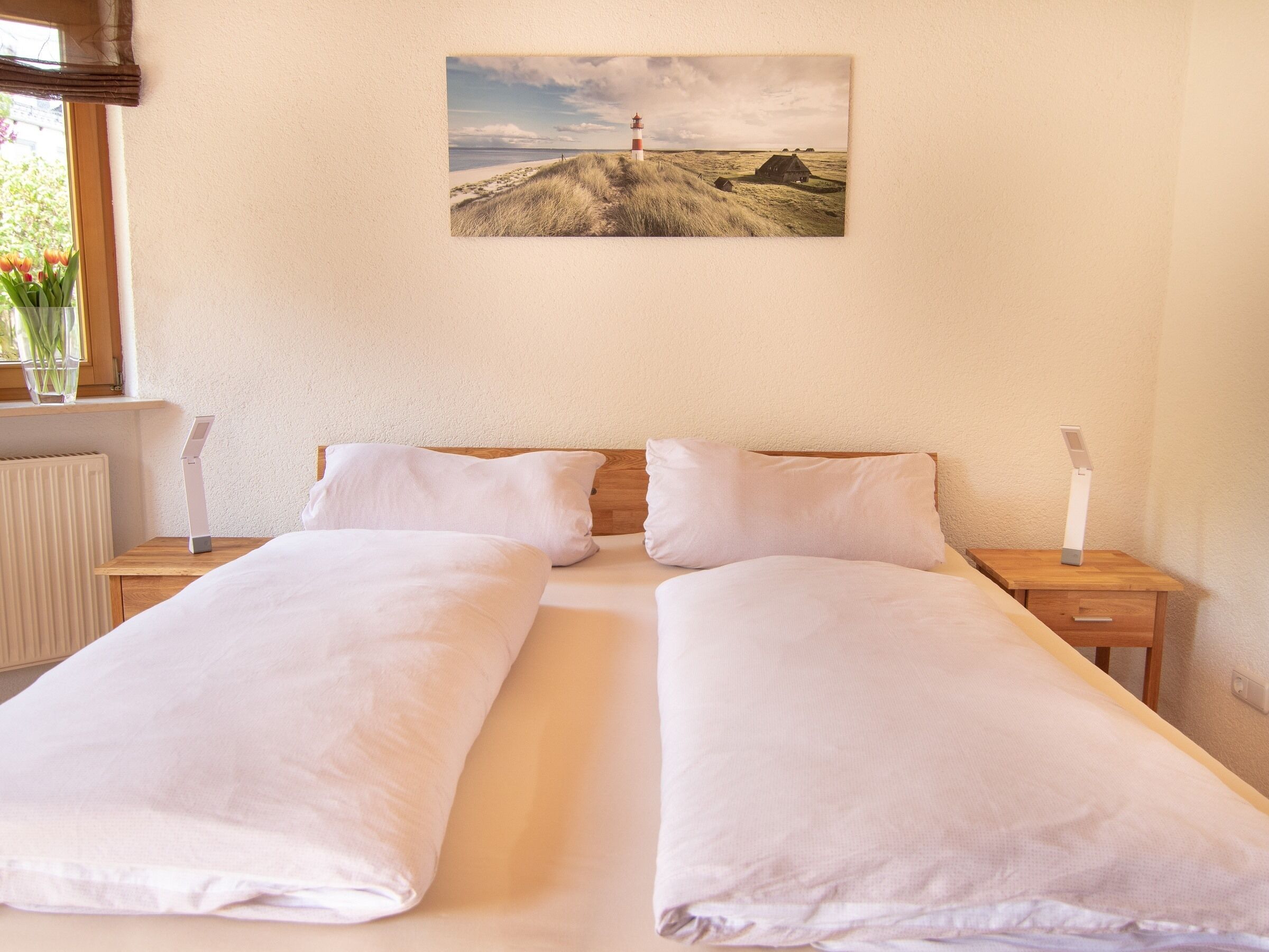 A double bed with white linens, wooden headboard, and two bedside tables with lamps.
