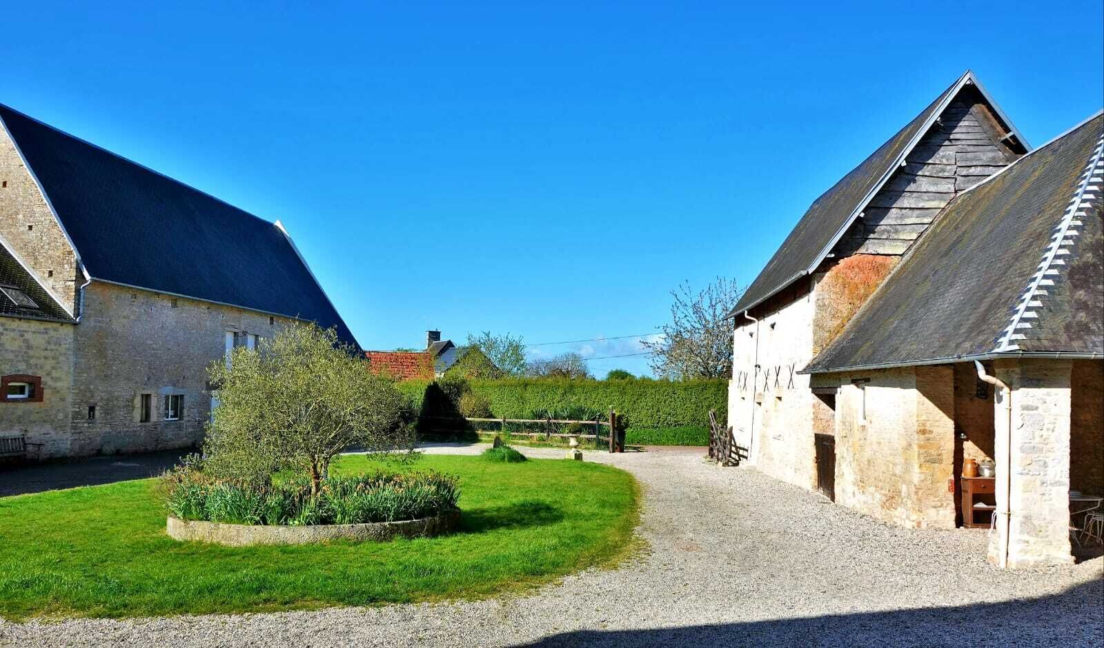 A rural property with stone buildings, a gravel driveway, and a well-maintained lawn.