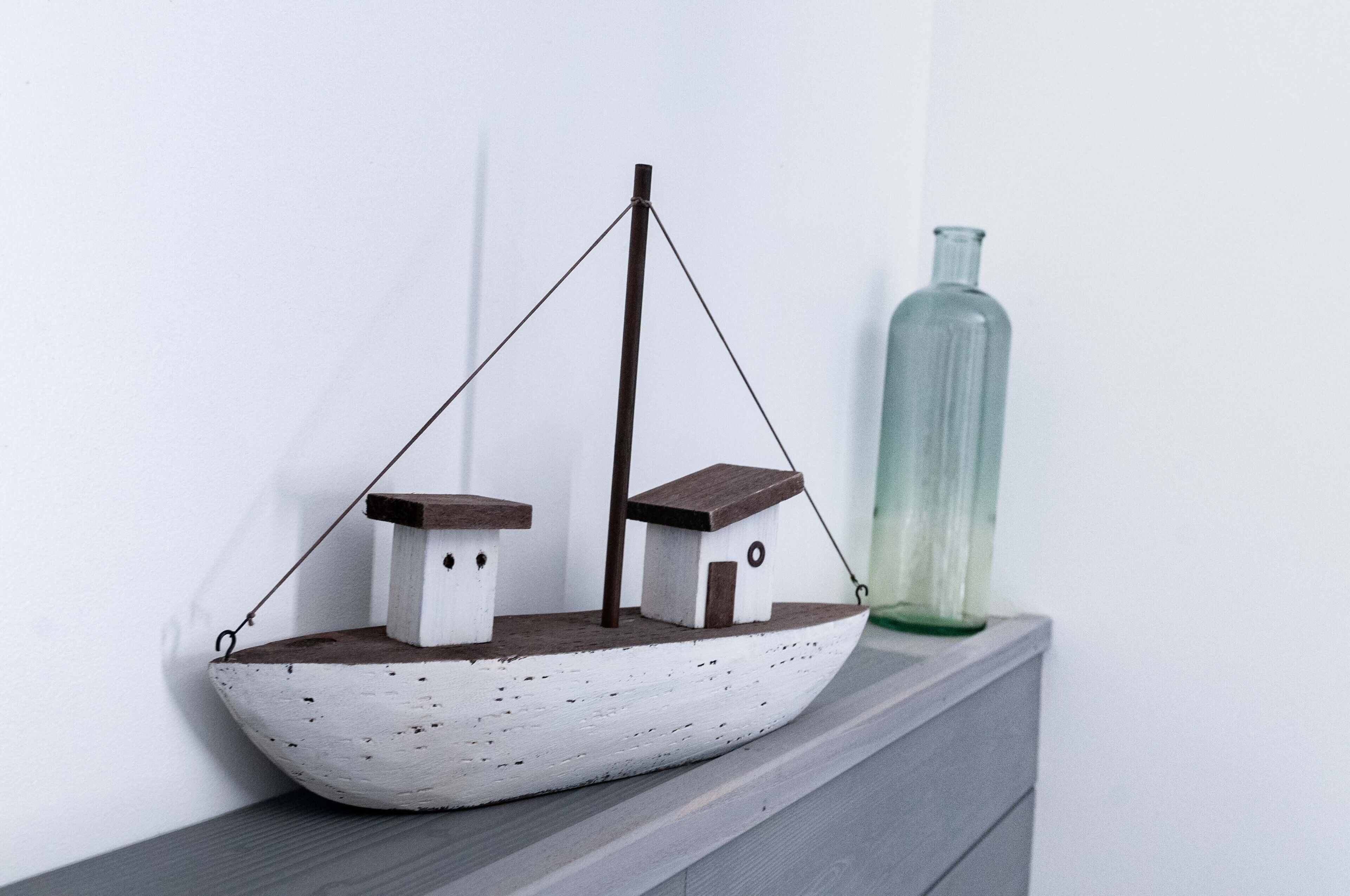 A model ship on a shelf next to a green bottle.