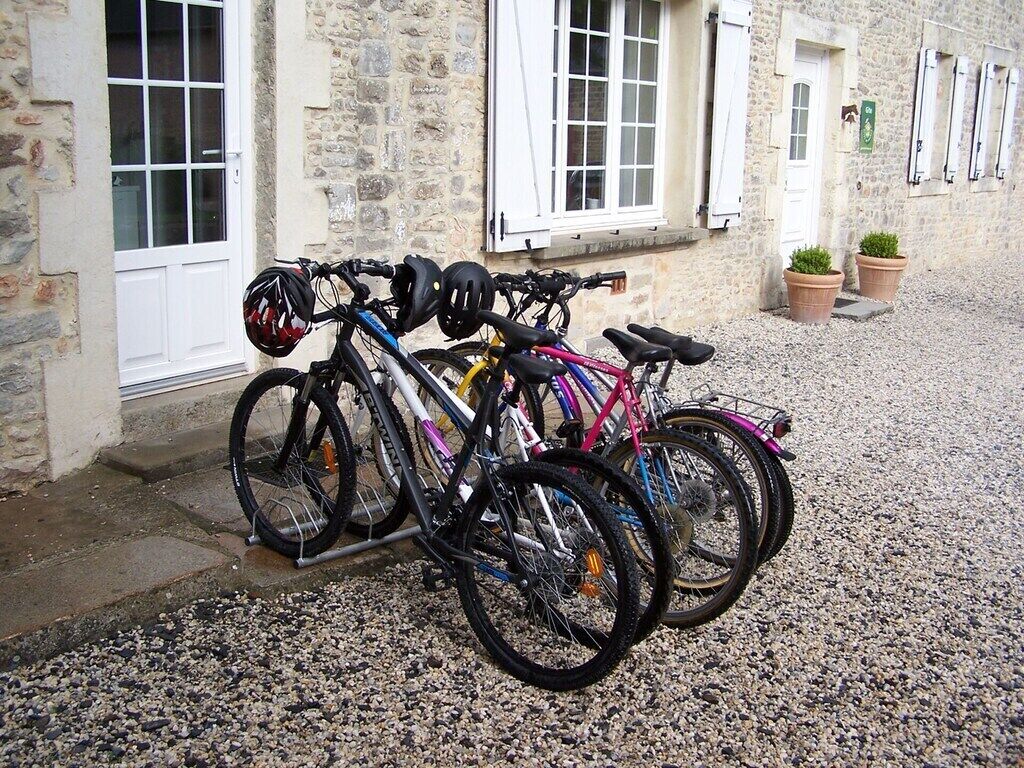Bicycles parked outside a stone building with a gravel ground.