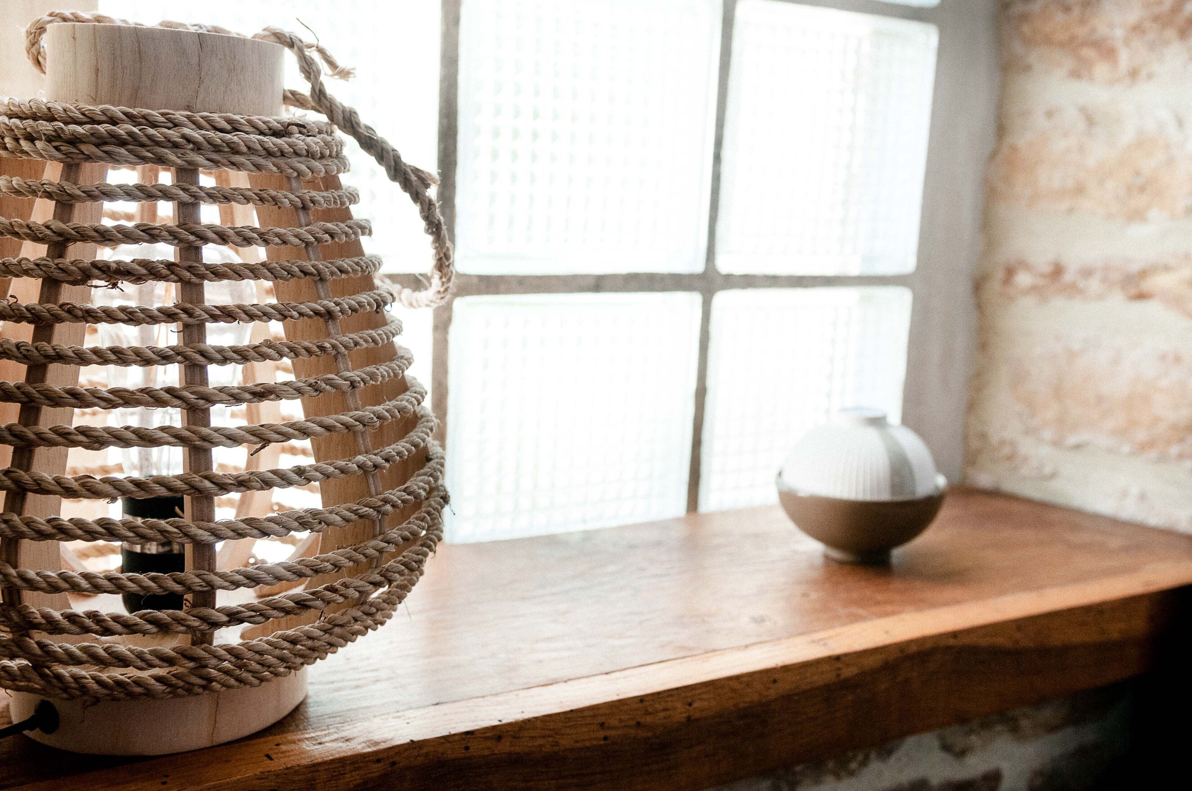 A wooden shelf with a woven rope lantern and a ceramic bowl.