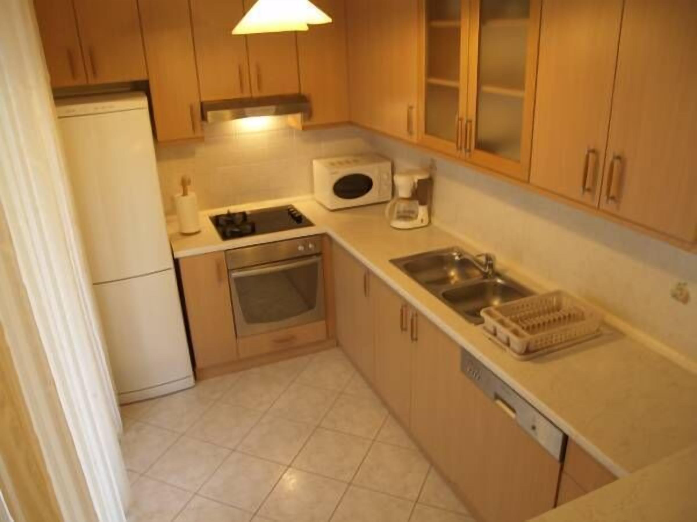A compact kitchen with a stove, microwave, sink, and oven.