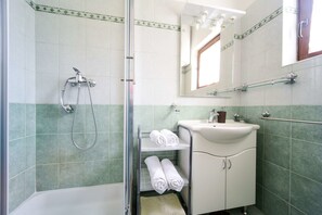 Un baño con ducha, lavamanos y espejo.