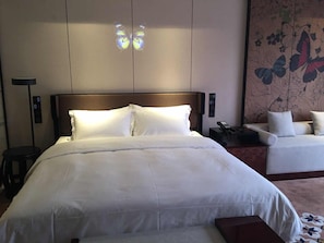 A hotel room with a large bed, a bedside table with a lamp, a small table, and a sofa. - Guangzhou Paco Hotel - Dongpu Teemall (Guangzhou)