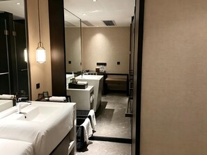 Un baño de hotel moderno con dos lavamanos, un espejo y una zona de ducha.