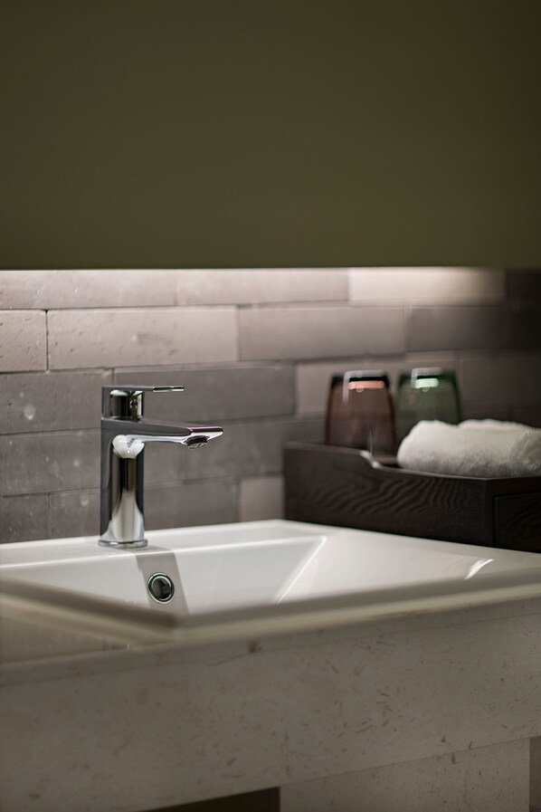 A bathroom sink with a modern faucet, a towel rack, and a soap dispenser.