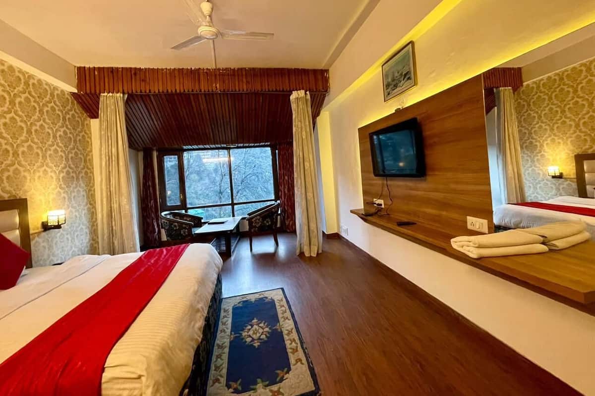 A hotel room with two beds, a TV, a wooden desk, and a window with a view.